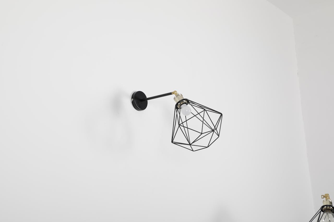 A minimalist wall lamp with a geometric design against a white wall, perfect for modern decor.