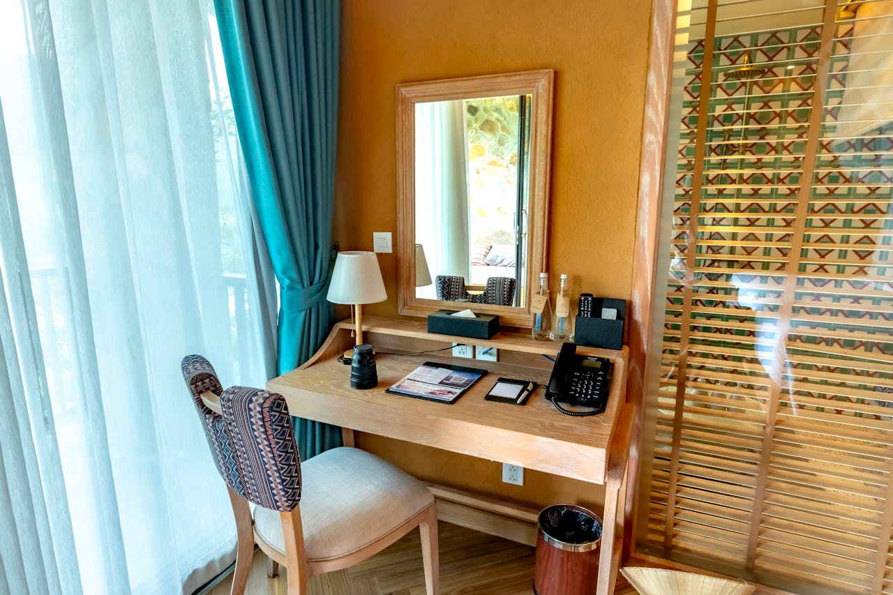 Elegant hotel room desk setup with mirror and accessories.