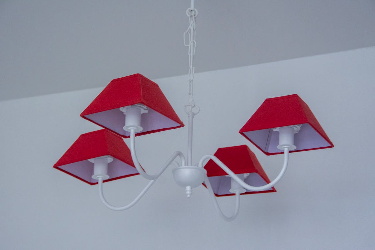 A minimalist modern chandelier with red shades hanging indoors, highlighting interior design and lighting.